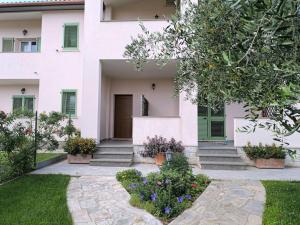 a white house with green shutters and flowers in a yard at Everything a bike ride away! 10 mins to the beach with free parking! in Marina di Grosseto
