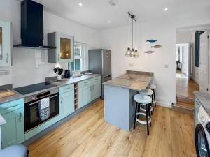 a kitchen with blue cabinets and a wooden floor at Beachside Cottage Minehead in Minehead