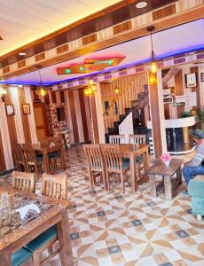 a restaurant with wooden tables and chairs and a person at D’SHIEKHS RESORT GUREZ in Kanzalwan