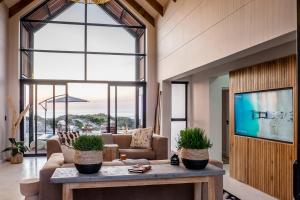 a living room with a couch and a tv at Thalassophile Beach House - Heated Pool in St. Helena Bay