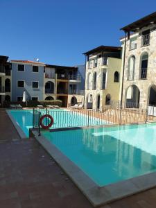 une grande piscine avec deux bâtiments en arrière-plan dans l'établissement La Muddizza appartement avec piscine, à Valledoria