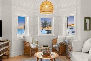 a living room with a couch and chairs and windows at Beachside Boho Retreat by Sydney Dreams in Sydney