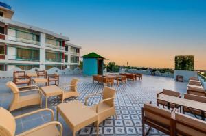 a patio with tables and chairs and a building at Grand Continent Morjim in Morjim