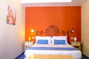 a bedroom with a bed with an orange wall at Hotel Baglio Di Scopello in Scopello