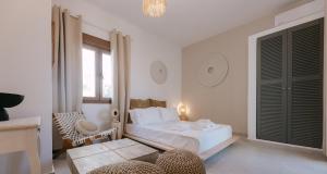 a white bedroom with a bed and a chair at Naxian Harmony Town Suites in Naxos Chora