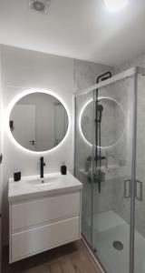 a bathroom with a sink and a shower with a mirror at Burela Mariña Playa in Burela de Cabo