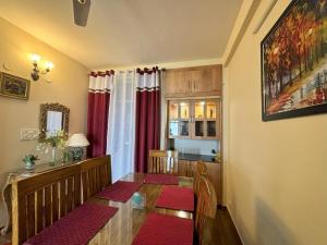 a dining room with a wooden table and red cushioned chairs at Rovers Suites - 2BHK Entire Luxury Apartment in Mussoorie