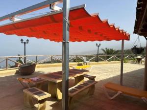 czerwony parasol na patio ze stołem i krzesłami w obiekcie TENERIFE ECOLIFE HOUSES by APARTAMENTOS ESTRELLA DEL NORTE w mieście Garachico +30 zdjęć