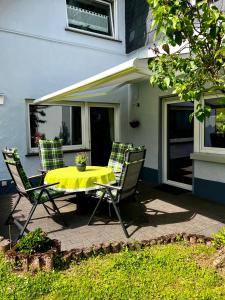 a yellow table and two chairs on a patio at Deine-Eifel-Ferienwohnung in Feusdorf