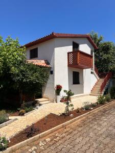a white house with a balcony and a brick driveway at Jasna in Poreč