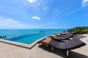 a swimming pool with chairs and the ocean in the background at Scenery Samui in Chaweng