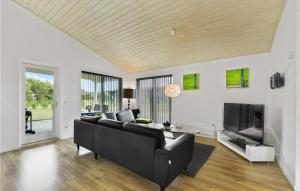 a living room with a black couch and a tv at Holiday Home Sydmarken Xi in Falen