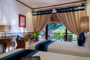 two beds in a room with a window at Riverside Boutique Resort, Vang Vieng in Vang Vieng