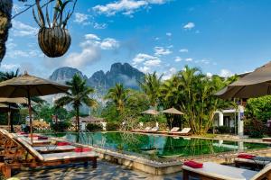 una piscina in un resort con montagne sullo sfondo di Riverside Boutique Resort, Vang Vieng a Vang Vieng