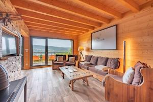 a living room with a couch and a tv at Chalet La Souris, chaleureux avec vue panoramique in Gérardmer