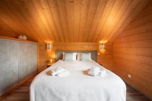a bedroom with a large white bed in a wooden ceiling at Chalet La Souris, chaleureux avec vue panoramique in Gérardmer