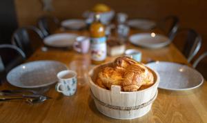 a wooden table with a basket of croissants on it at Chalet La Souris, chaleureux avec vue panoramique in Gérardmer