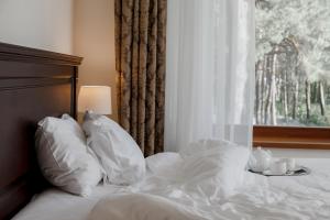 a bed with white sheets and pillows next to a window at Pu&scaron;ynė in Bir&scaron;tonas