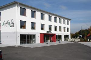 a large white building with a red door at Alpenflair Hotel in Buchloe