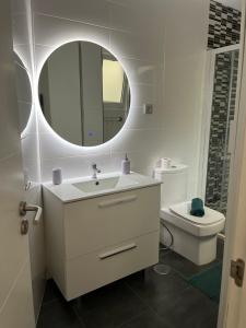 a bathroom with a sink and a mirror and a toilet at Yudelmys confort in Las Palmas de Gran Canaria