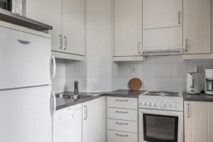 a white kitchen with white cabinets and a sink at Nordic Glow Studio in Rovaniemi