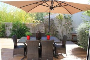 a table with chairs and an umbrella on a patio at Villa CLOTESS in Dompierre-sur-Mer