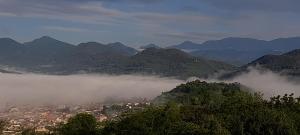 a view of a city in the mountains with clouds at Spacious Country House for 8 near Olot Remote Work & Nature Escape in Olot +65 photos