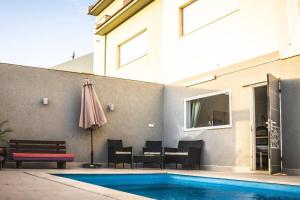 a patio with a pool and an umbrella next to a building at המקום של עופרי - Ofri's place in Arad
