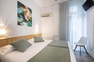 1 dormitorio con 1 cama blanca y 1 silla en Pensión Donostiarra, en San Sebastián