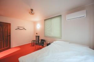 a bedroom with a bed and a chair and a window at Chungking Mansions Busan in Busan