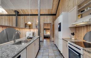 a kitchen with white appliances and wooden walls at Pet Friendly Home In Oksbøl With Sauna in Oksbøl +13 photos