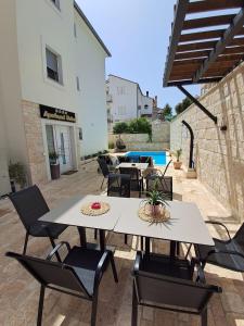a patio with tables and chairs and a pool at Apartmani Datea in Grebaštica