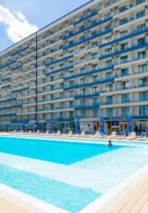 a large building with a swimming pool next to a hotel at Blooming by the Sea - camere cu vedere frontală spre mare in Olimp