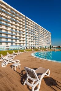 a row of lounge chairs in front of a large building at Blooming by the Sea - camere cu vedere frontală spre mare in Olimp
