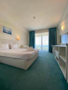 a bedroom with a large bed and a large window at Blooming by the Sea - camere cu vedere frontală spre mare in Olimp