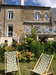 two chairs sitting in the grass in front of a building at La maison du lac in Saint-Hilaire-du-Harcouët