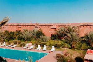 a resort with a pool and chairs and a building at Maison D'h&ocirc;te Amridil in Skoura
