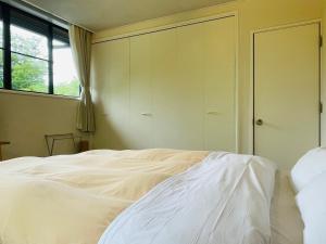 a bedroom with a white bed and a window at Hatago Tsubakiya in Yamanakako