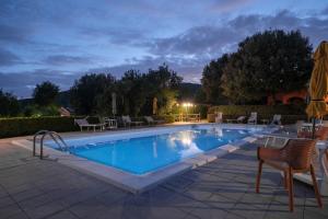 a swimming pool at night with chairs and tables at Agriturismo Niccoland in Grosseto