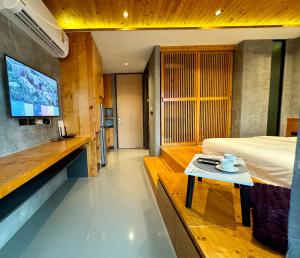 a room with a bed and a table with a tv at Mira Naiharn, Minimalist Design & Mountain View at Relife Windy in Rawai Beach