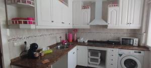 a kitchen with white cabinets and a sink and a microwave at Nuria's home in Calanda