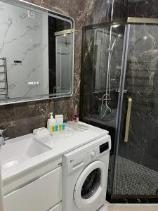 un bagno con lavatrice e lavandino di KERUEN SARAY APARTMENTs 20-1 a Türkistan