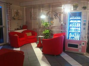 - un salon avec des chaises rouges et une machine à soda dans l'établissement La Grange de Marie, à Nitry