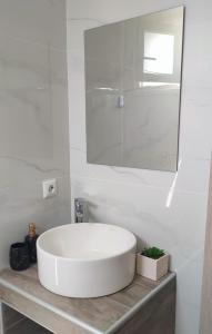 a white bathroom with a sink and a mirror at Vigla summer house! in Paralia Sikias
