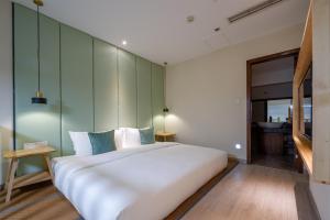 a bedroom with a large white bed and green walls at Mount Emei Heyuan Serene Residence Hot Spring Hotel in Emeishan City