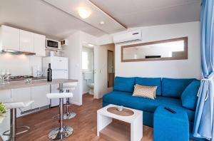 a living room with a blue couch and a kitchen at San Antonio 2 mobile homes in Biograd na Moru