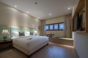 a bedroom with a large white bed and a window at Mount Emei Heyuan Serene Residence Hot Spring Hotel in Emeishan City