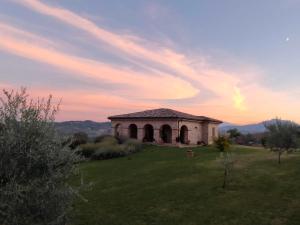 a building in a field with a sunset in the background at Villa Liliana, Exclusive Property in Monte Rinaldo