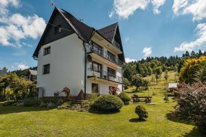 a large white house with a black roof at Apartamenty Sielska 102 in Szlachtowa