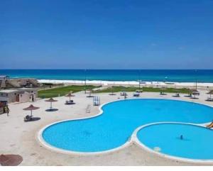 a large swimming pool with the ocean in the background at Summer Doors - Families Only in Dawwār ‘Abd Allāh